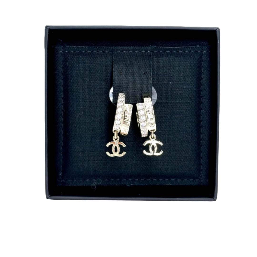 Chanel hoop earrings with signature logo and embellishments displayed in a black box