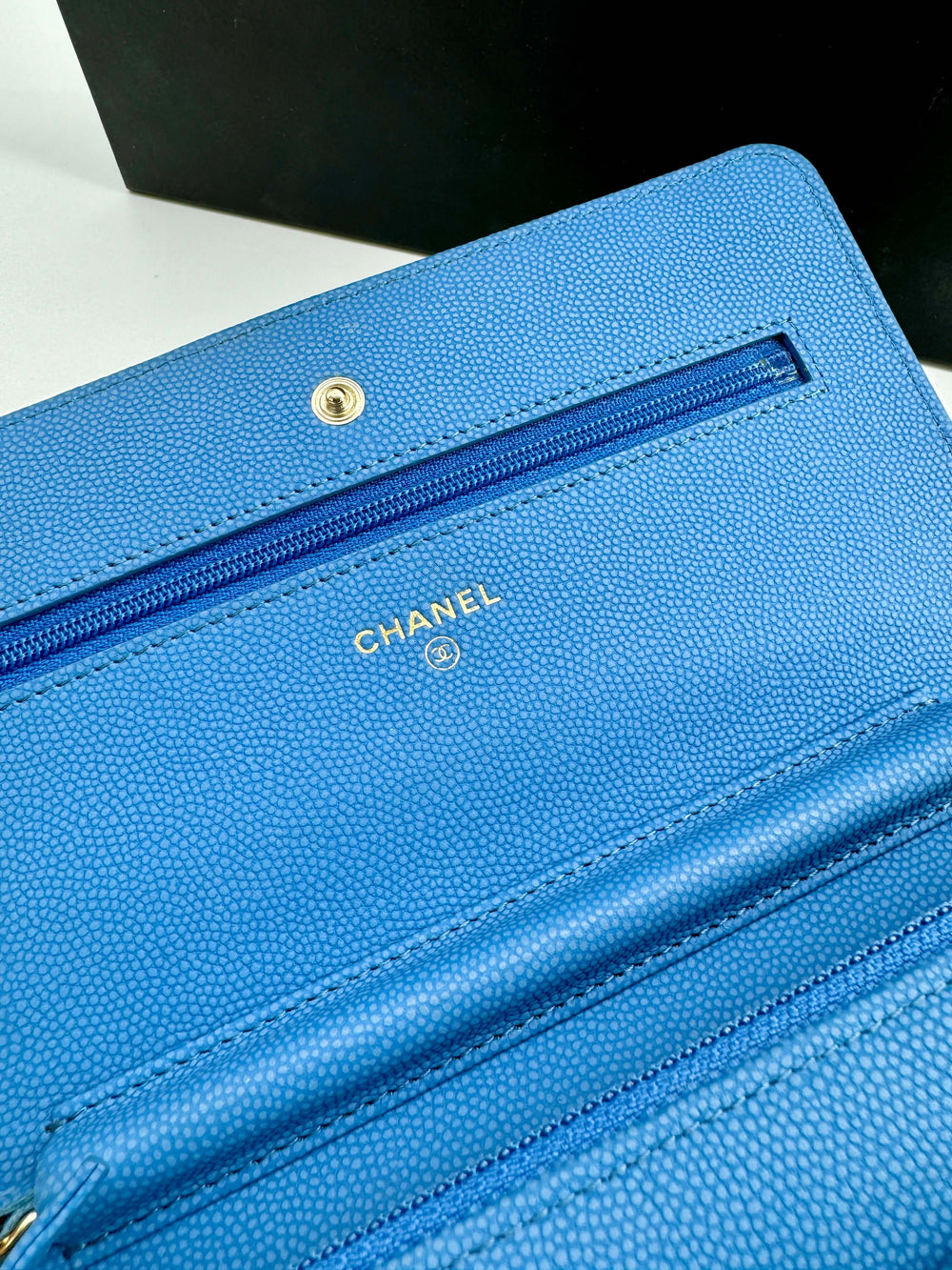 Close-up of Chanel blue caviar Wallet on Chain (WOC) showing interior compartments and gold logo detailing.