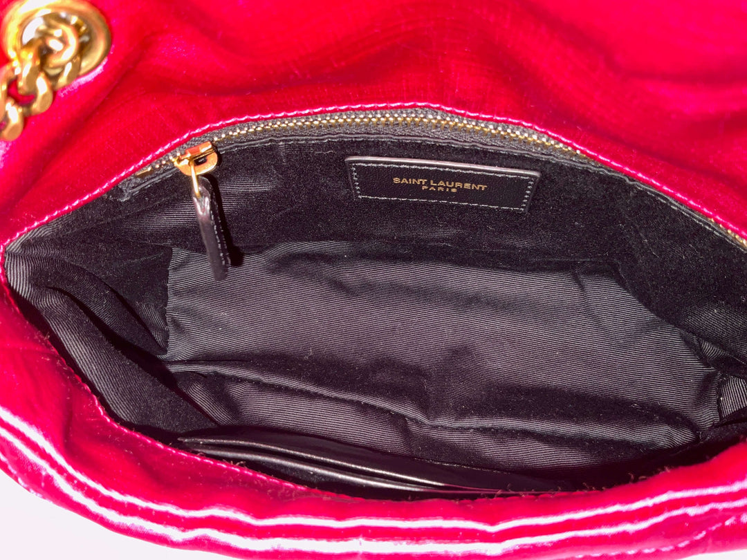 Interior of a red Saint Laurent handbag with a black lining and gold zipper detail.