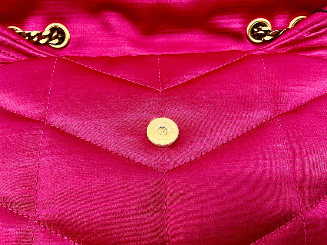 Close-up of a pink quilted leather bag with gold chain details and a snap button closure.