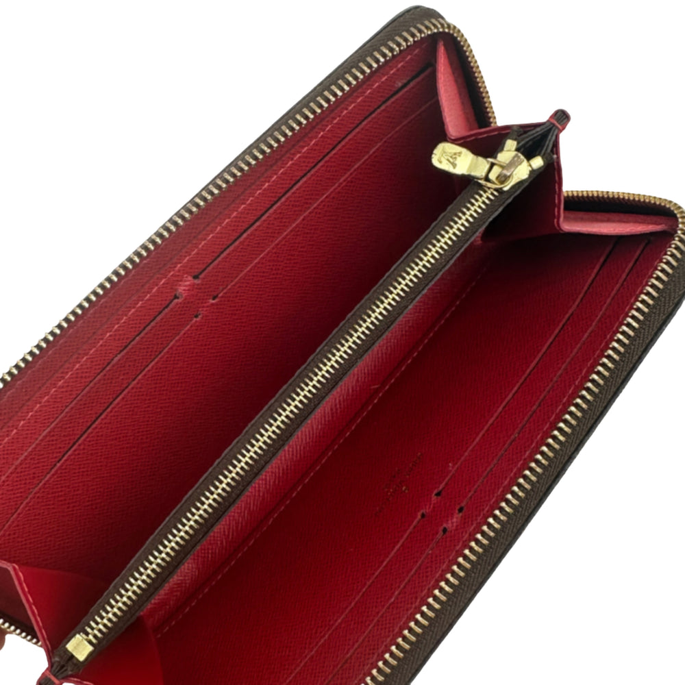 Interior view of LOUIS VUITTON Damier Ebene Clemence Wallet with red lining and gold zipper.