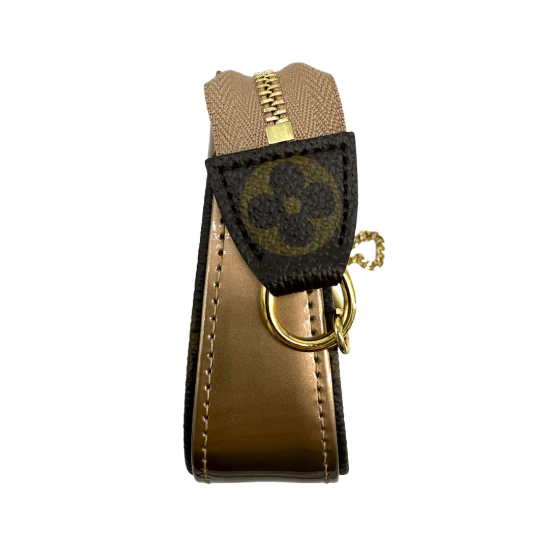 Louis Vuitton Metallic Vernis Mini Pochette zip detail showcasing gold-tone hardware and iconic monogram pattern.