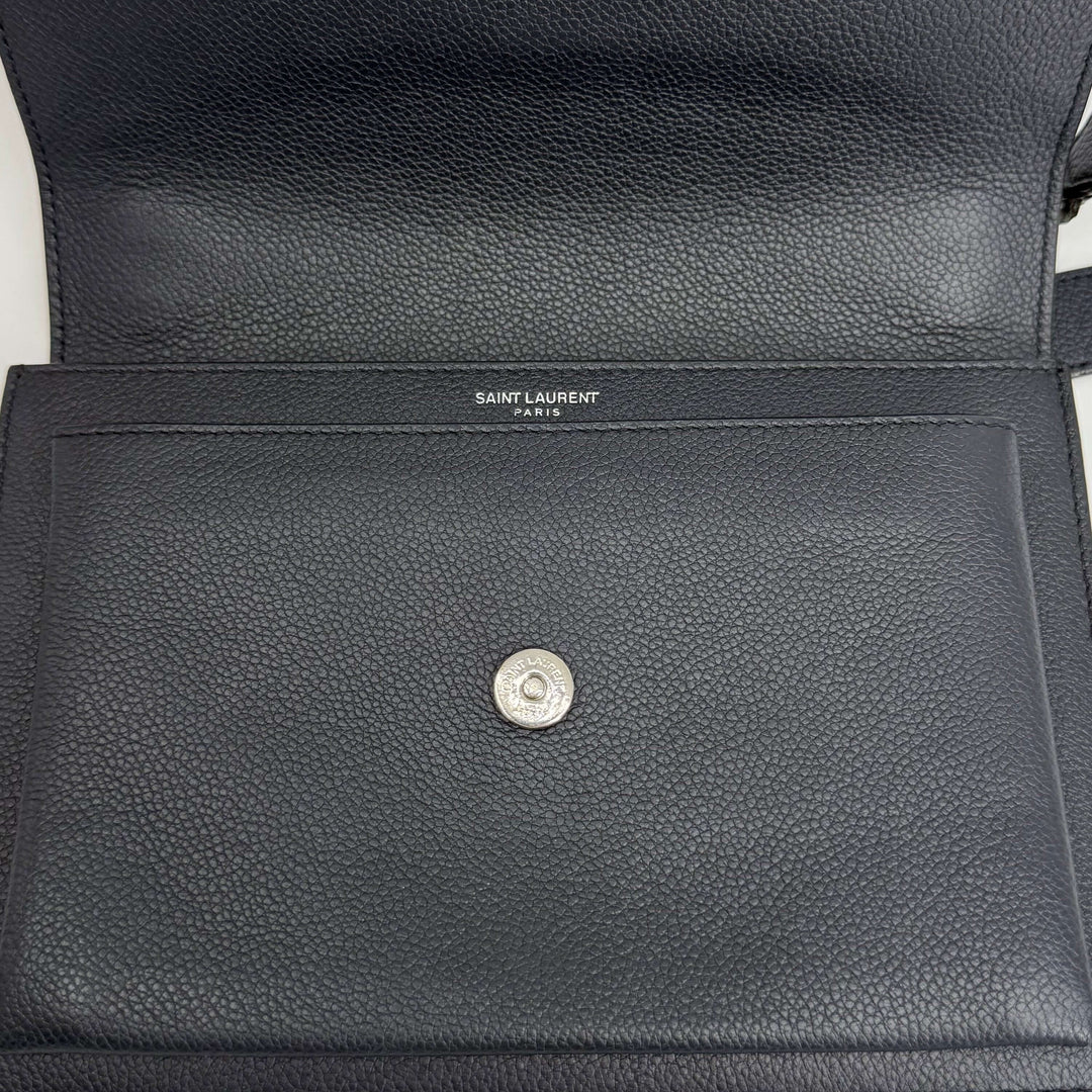 Interior view of Authentic Saint Laurent Grained Calfskin bag showing logo and snap closure, elegant craftsmanship.