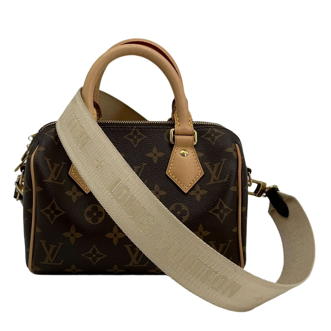 Louis Vuitton jacquard strap in beige attached to a monogram handbag with tan leather accents.