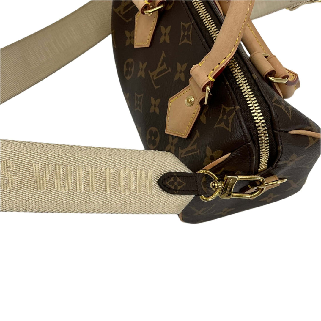 Beige Louis Vuitton Jacquard Strap attached to dark brown monogram handbag, showcasing fine craftsmanship and luxury design.