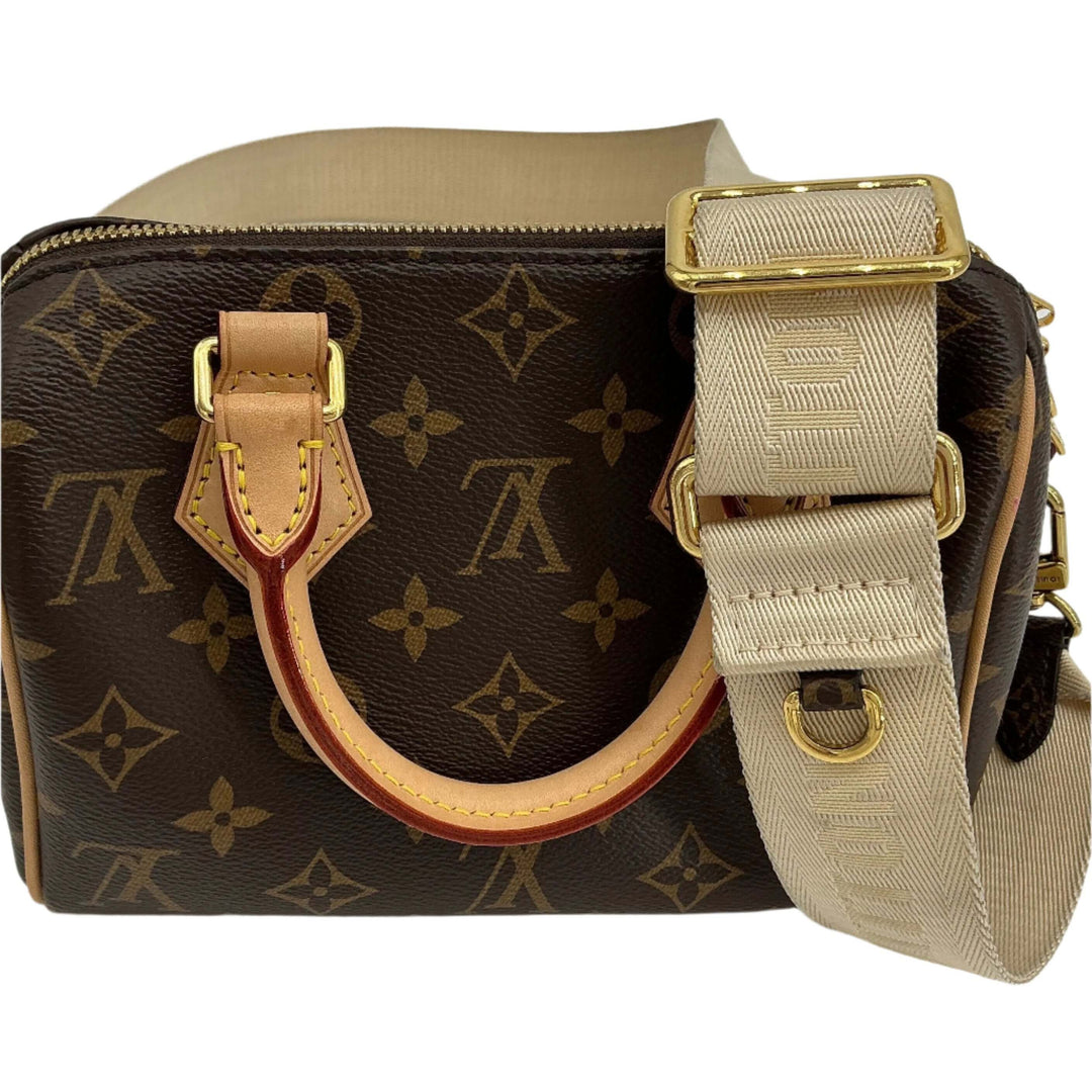 Louis Vuitton Jacquard Strap in Beige attached to a Louis Vuitton monogram handbag featuring gold hardware and a leather handle.