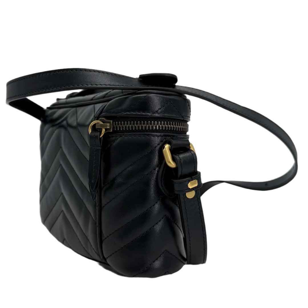 Gucci black calfskin matelassé mini GG Marmont backpack side view showcasing chevron quilting and aged gold hardware.