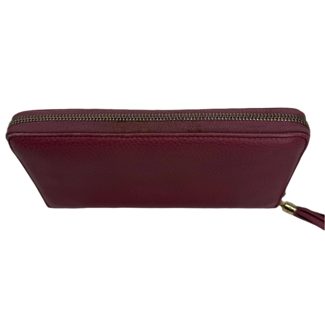 Top view of a Gucci Zippy Leather Wallet in mauve pink with a zip-around closure and tassel detail.