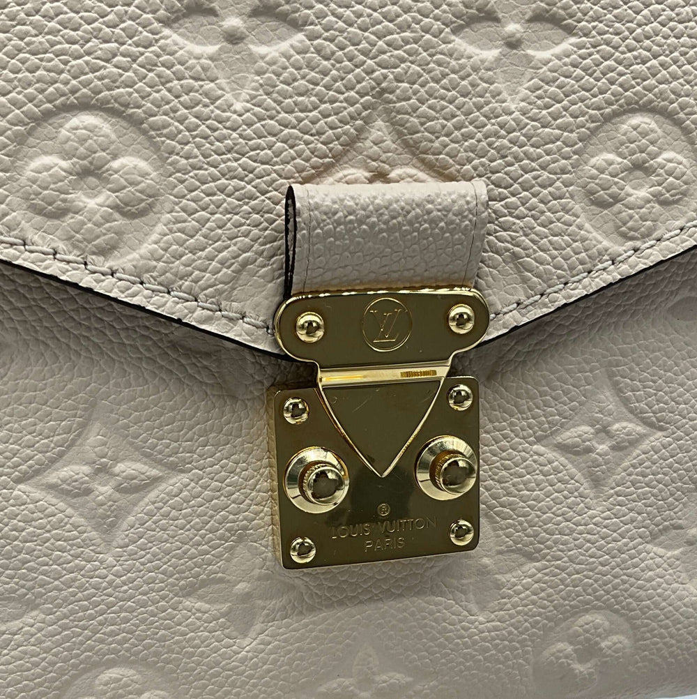 Close-up of Louis Vuitton Empreinte Braided Pochette clasp in beige caramel calfskin leather with gold-tone hardware.