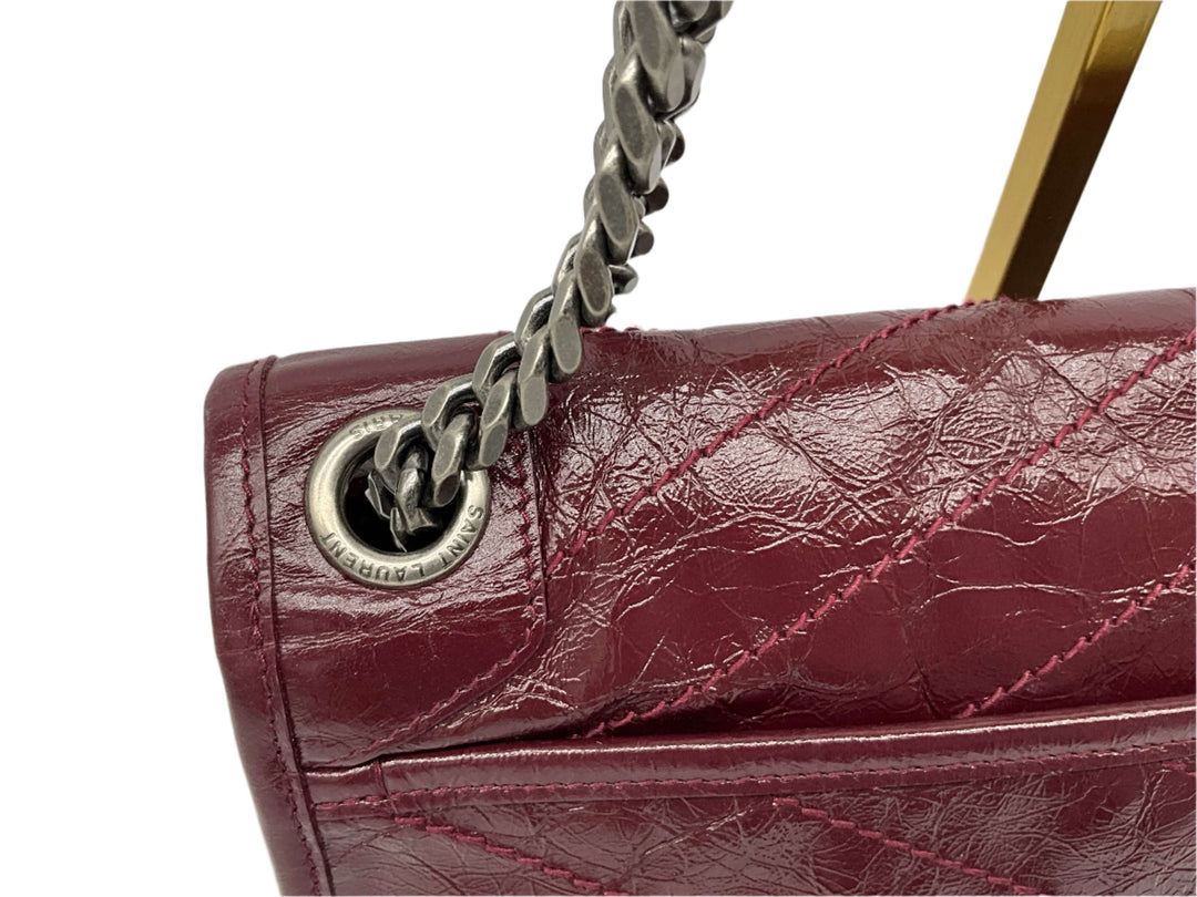 Close-up of crinkled calfskin texture on the Saint Laurent Niki Chain Satchel in Rouge Legion color with chain detail.