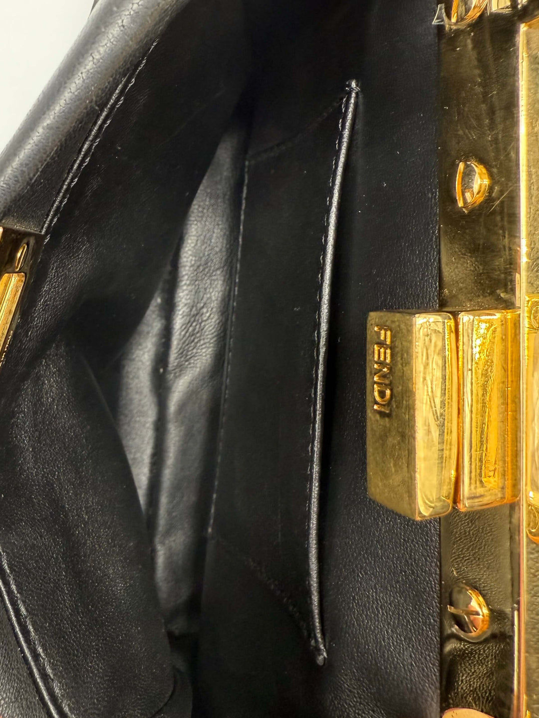 Interior view of Fendi Nappa Crystal Studded XS Peekaboo Satchel, showcasing signature black leather and gold hardware.