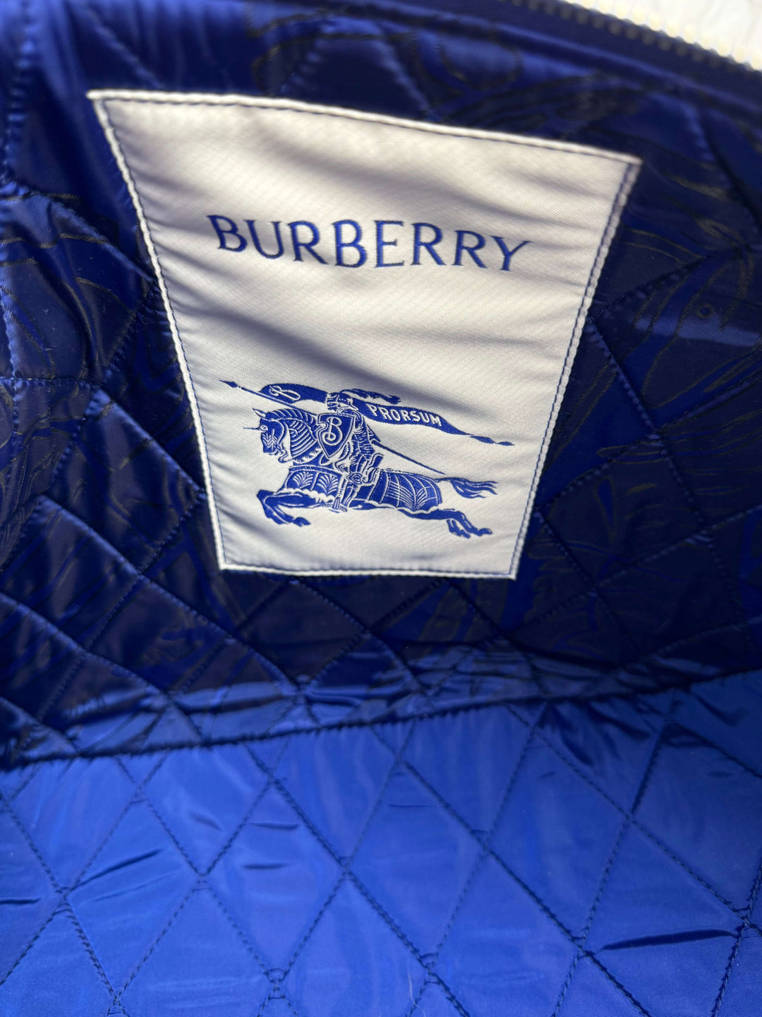 Inside view of a Burberry crossbody bag showcasing the iconic logo on blue fabric.