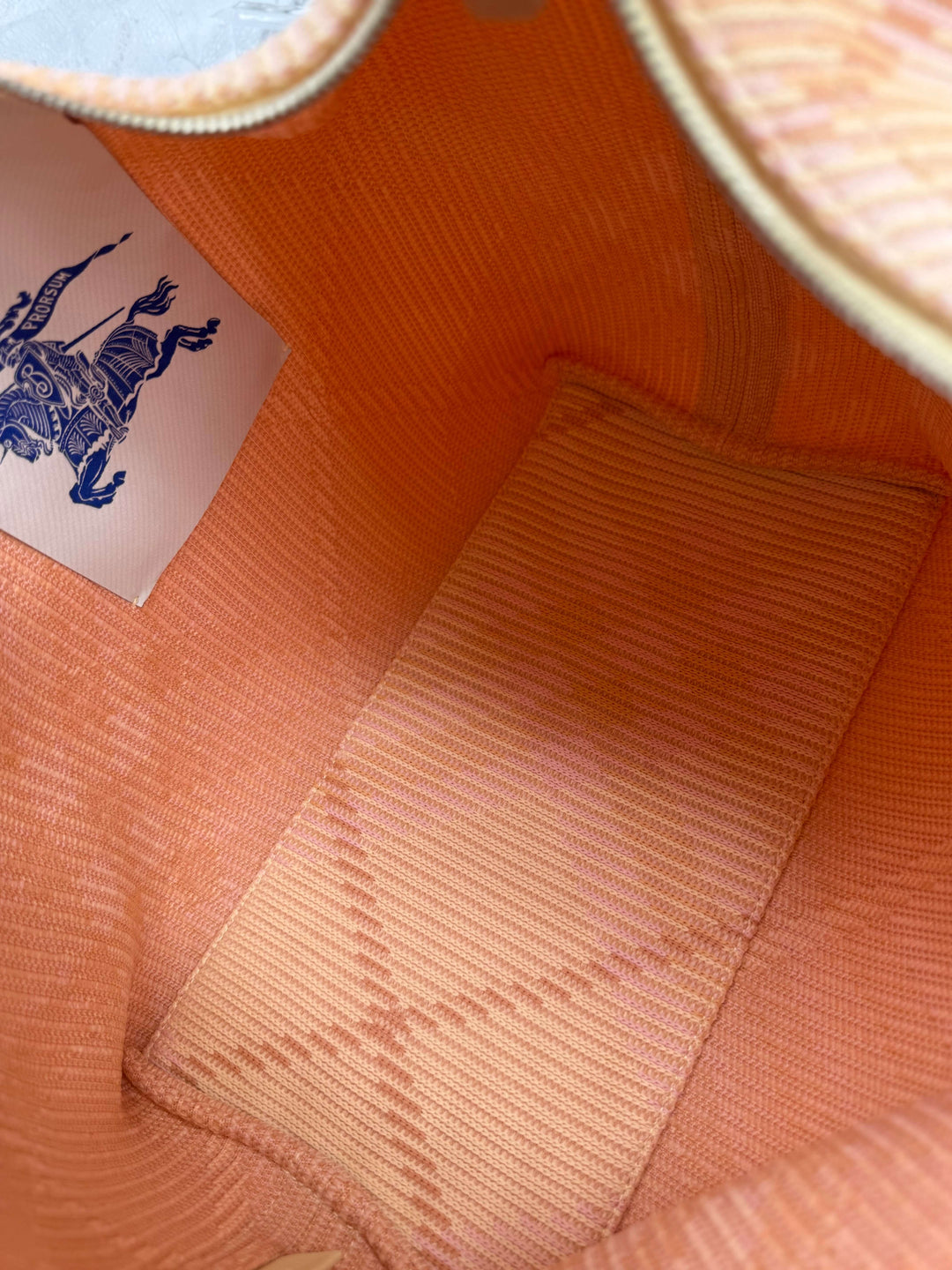 Interior view of Burberry Canvas Peg Medium Duffle Bag in vibrant sherbert color with logo tag and lined fabric.